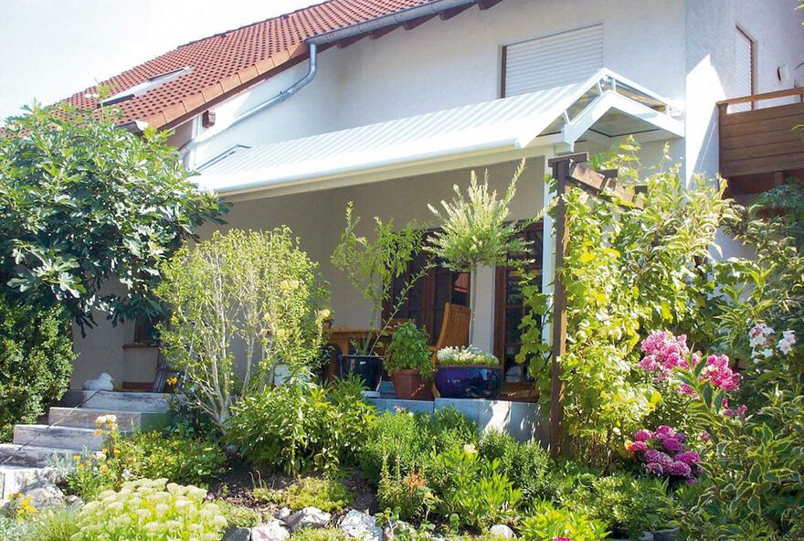 Eine Wintergartenmarkise in einem schön bepflanzten Garten