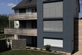 Metallfarbene Roffstore an einem Mehrfamilienhaus