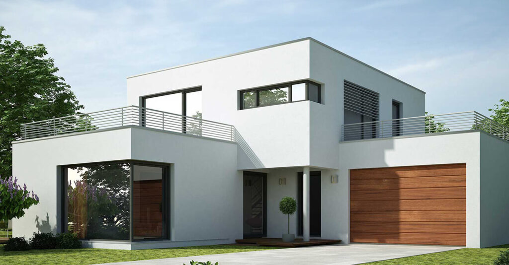 Modernes zweistöckiges weißes Haus mit Flachdach, großen Fenstern und hölzernen Garagentoren. Neben dem Eingang steht ein kleiner Baum und die Auffahrt führt zur Garage. Umgeben von Grün unter einem klaren Himmel.