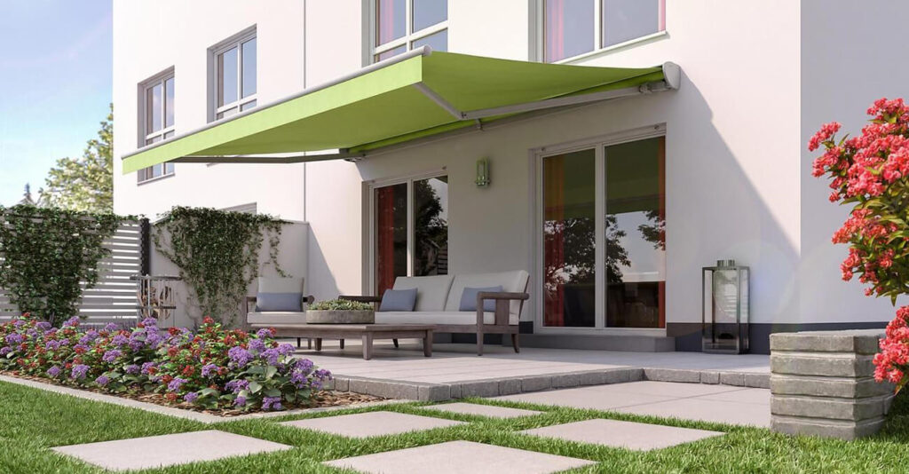 Grüne Gelenkarmmarkise, die über einem Sitzbereich auf einer Terrasse montiert ist.